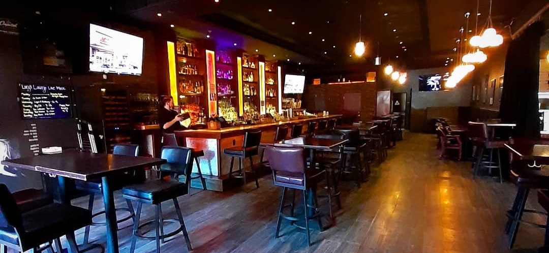 Inside Lucy's Lounge: the long bar, high-top tables and pendant lights over a wood floor